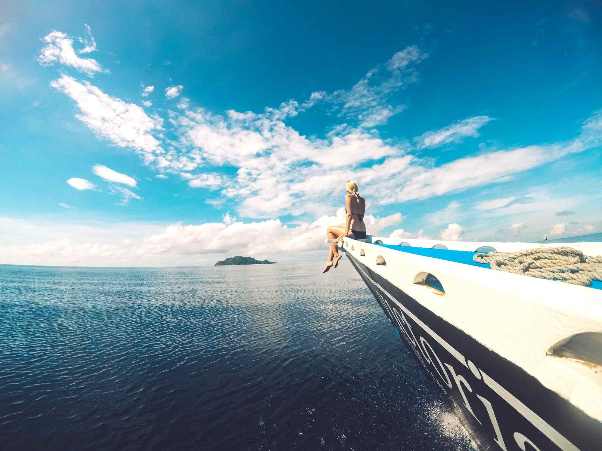 A picture from one of our 5 most popular excursions near Dumaguete. A boat sailing towards Apo Island in the Philippines and a person sitting in the front