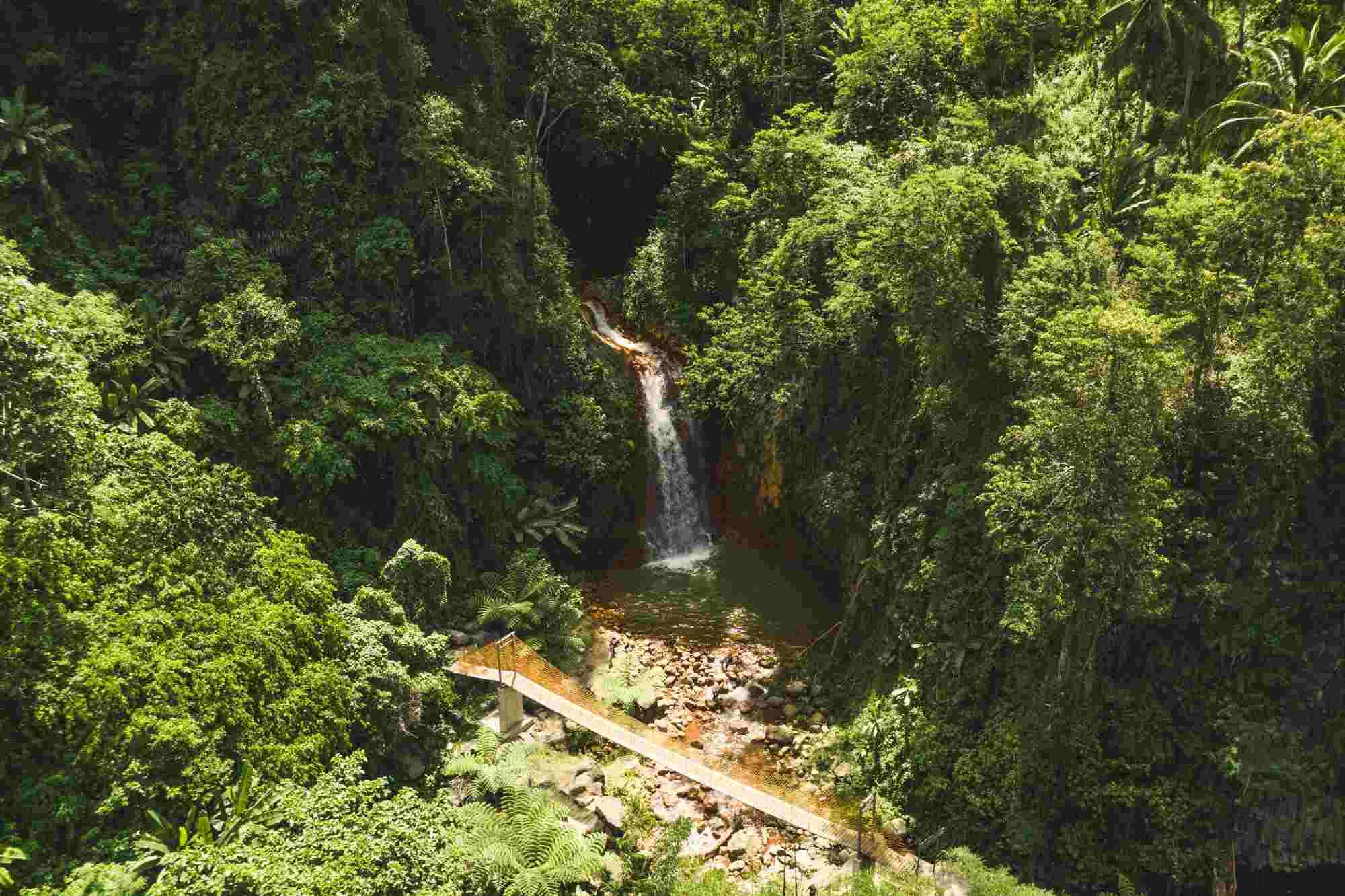 Red rock water fall or Pulangbato Falls in Valencia surrounded by lush green nature and a bridge