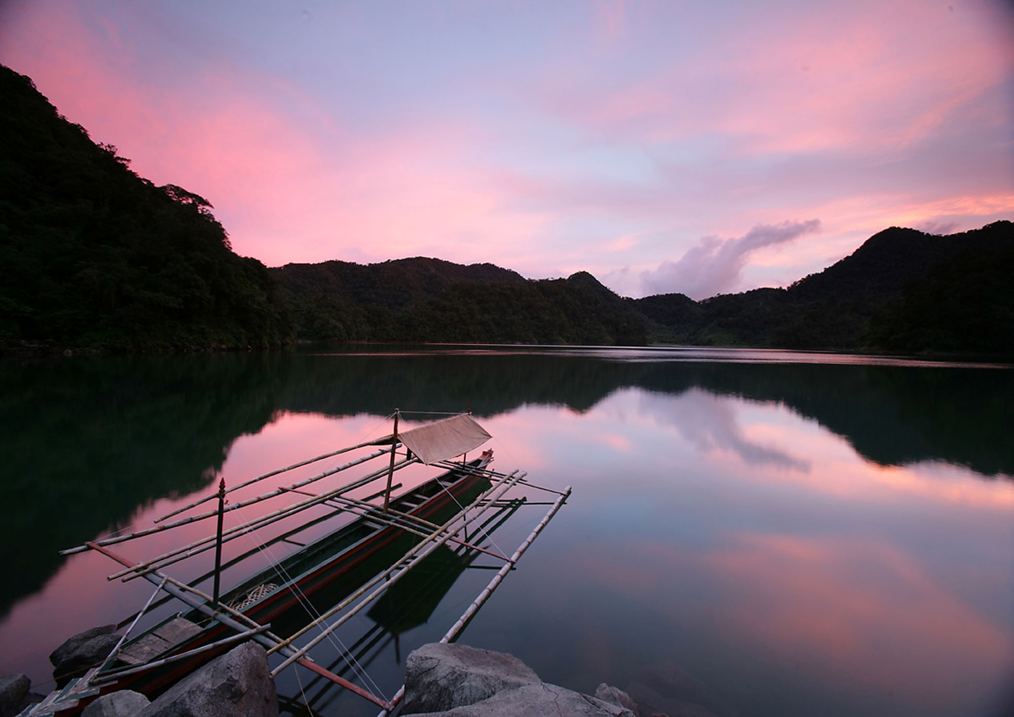 Sunset over the Twin lakes with a little boat in the Philippines which is one of most popular excursions near Dumaguete