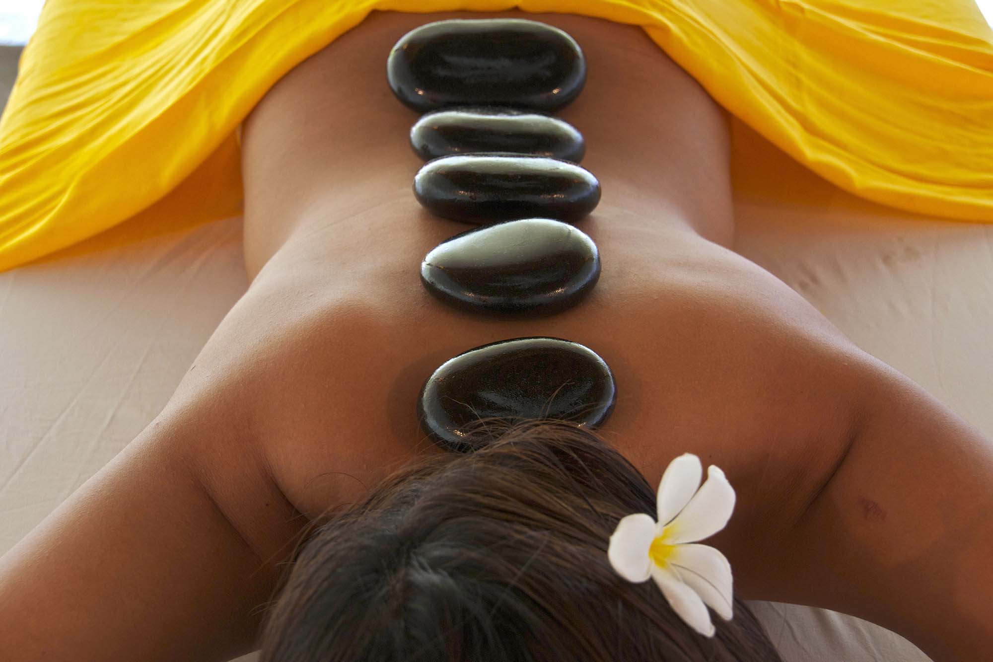 Hot smooth basalt stones placed on the spine on a woman during a hot stone massage