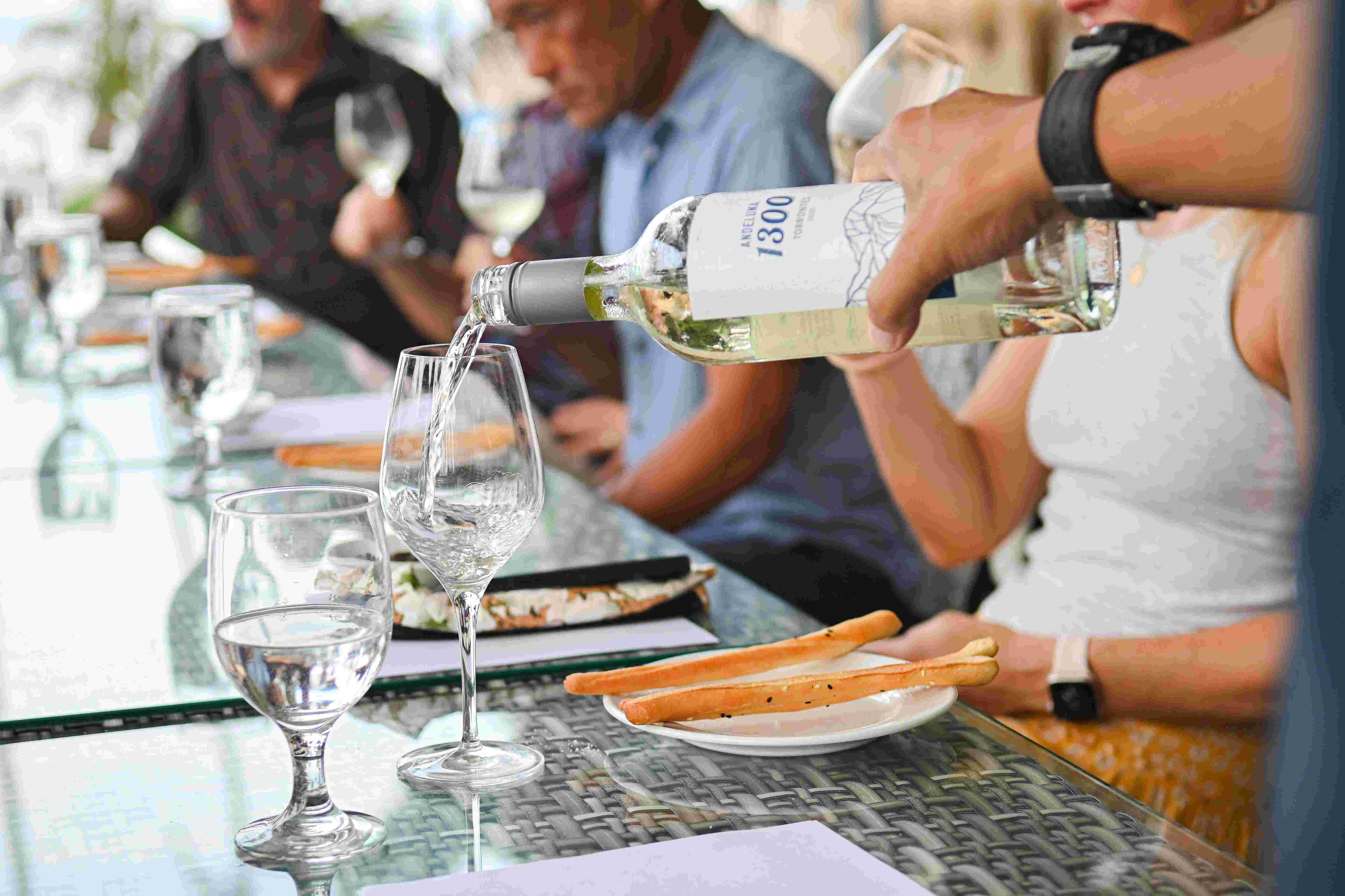 A man pouring white wine in to a glass in a wine tasting in the Philippines at Atmosphere Resorts & Spa.