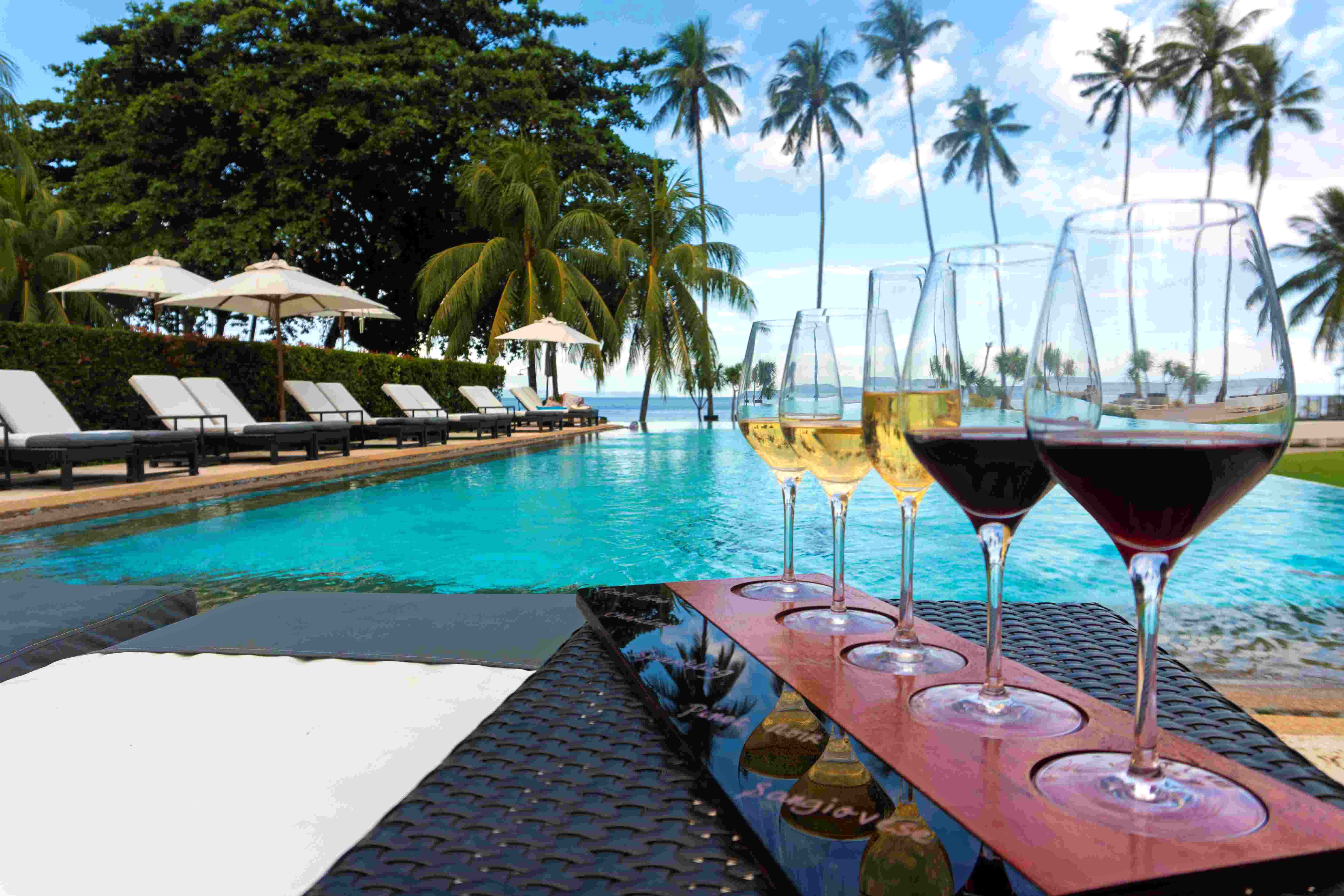 Wine glasses with red and white wine on a wine flight next to the pool in the Philippines at Atmosphere Resort & Spa.