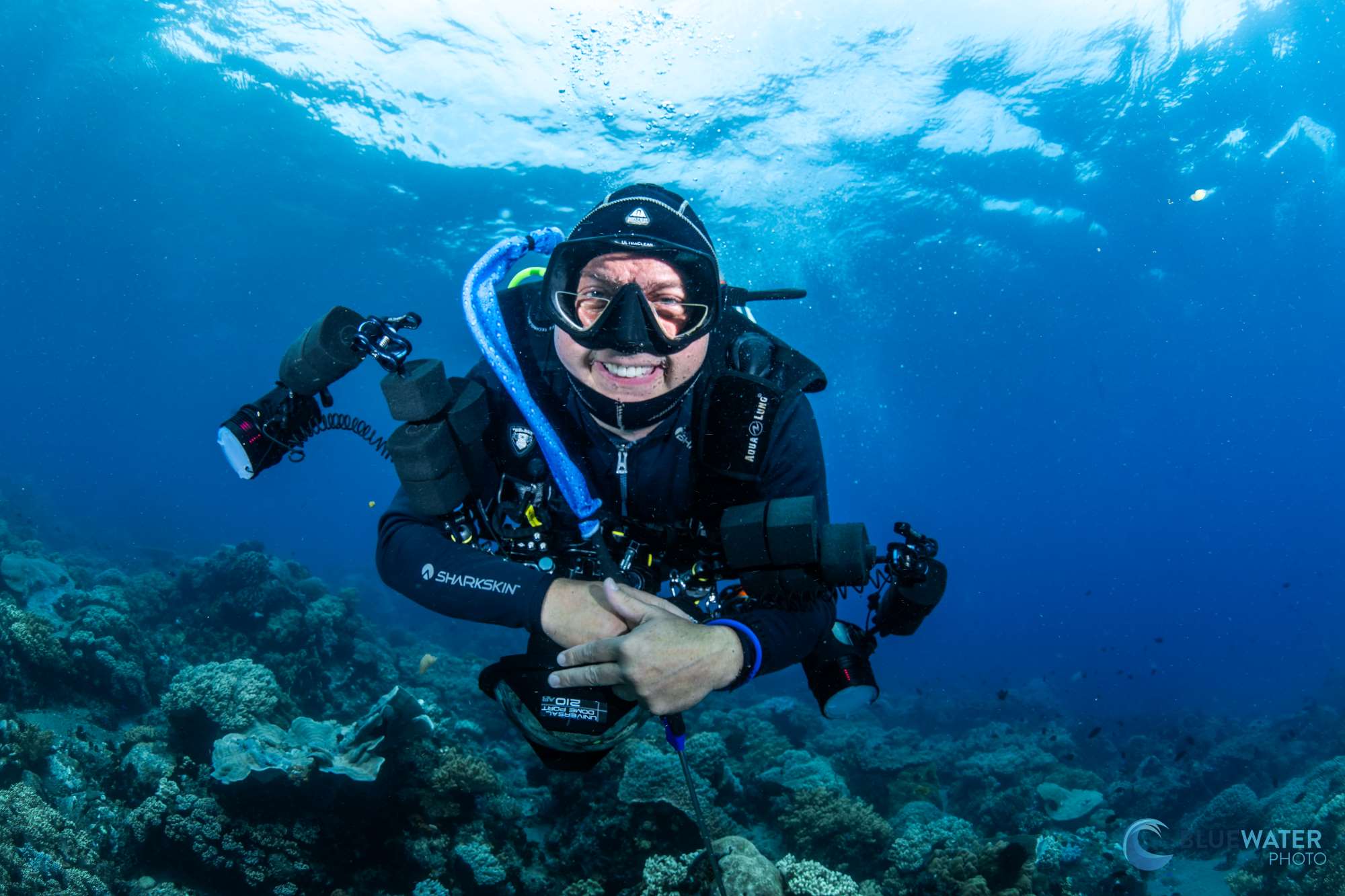 A picture of a diver smiling underwater, holding a camera